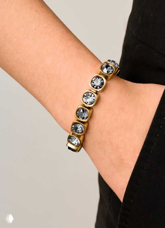 Браслет Dyrberg Kern с крупными круглымі кристаллами в золотой оправе, кадр запястья модели на нейтральном фоне без лица.