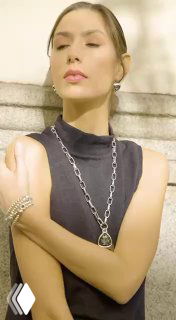 Модель в тёплом свете в чёрной одежде демонстрирует колье и браслет из коллекции AMARRE от Ciclon, рекламный кадр магазина Rosone.