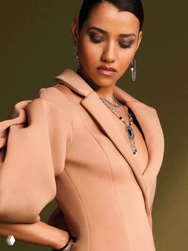 Модель в пудровом жакете демонстрирует комплект украшений Coeur de Lion: серьги, колье и подвески, подчёркивающие деловой стиль.