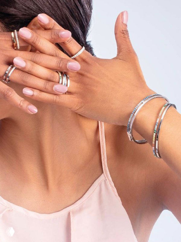 Крупный план рук и шеи модели: несколько колец, браслетов и серьги из коллекции Coeur de Lion — акцент на сочетании металлов и форм.