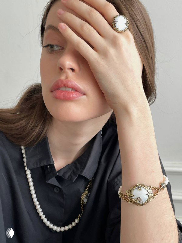 Модель прикрывает глаз рукой, видны жемчужное кольцо и браслет Fiore di Firenze; каталог Rosone, художественная композиция подчёркивает аксессуары.