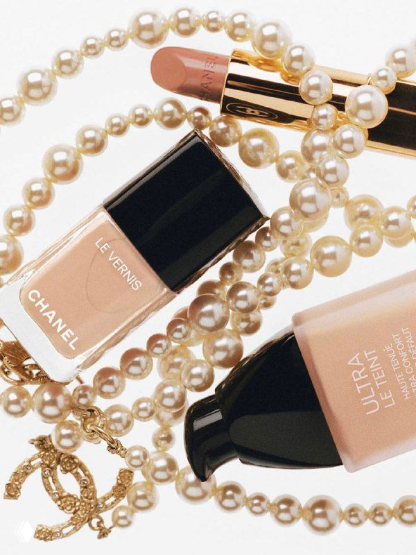 Плоская композиция: косметика Chanel и нити жемчуга, сочетание бьюти-продуктов и украшений в fashion-стилистике.
