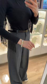 Зеркальное селфи в магазине: рука в браслете на фоне витрины с украшениями, часть образа и интерьер бутика видны в отражении.