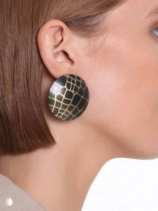 Крупный план наушной аксессуар круглой формы из металла KATERINA VASSOU, видена часть профиля модели, акцент на фактуре и геометрическом узоре металла.