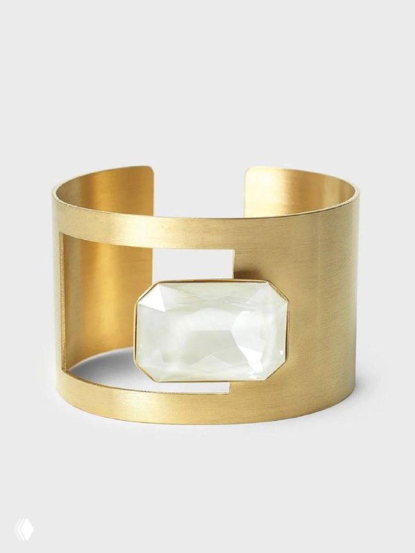 Широкий металлический браслет-манжета KATERINA VASSOU с крупной прямоугольной вставкой прозрачного камня на светлом фоне, демонстрация формы и отделки.