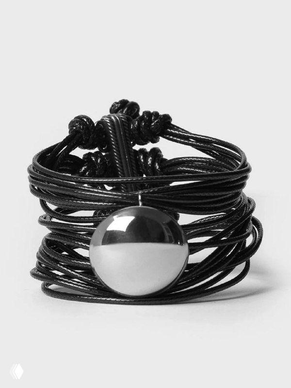 Кожаный многослойный браслет с крупной круглой металлической застёжкой или декоративной деталью от KATERINA VASSOU, акцент на коже и металле.