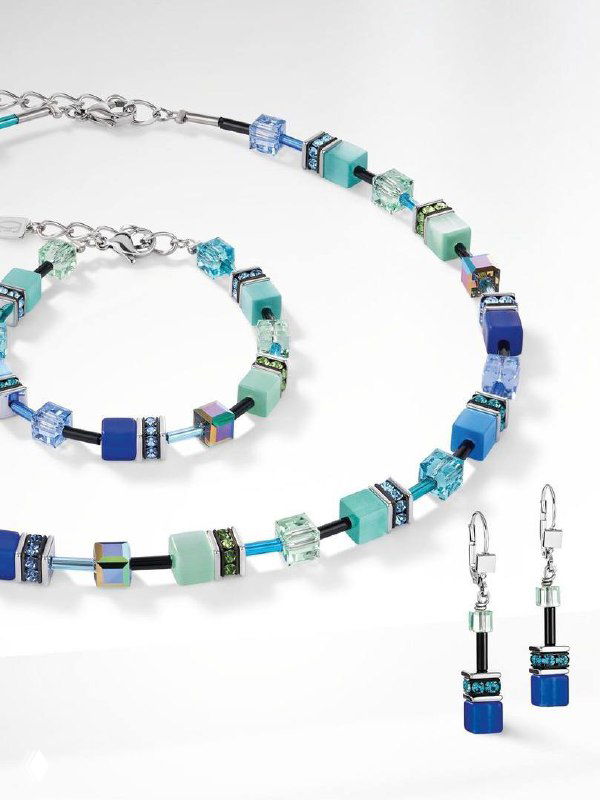 Крупный план украшений Coeur de Lion: ожерелье, браслет и серьги в оттенках синего и бирюзы с геометрическими кубическими элементами.