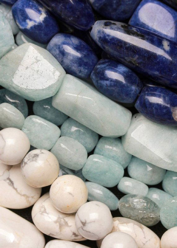 Крупные полированные натуральные камни разных оттенков синего и бирюзового, подготовленные для сборки ожерелий коллекции Arctique — вид текстуры и цвета.