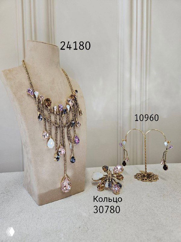 Крупное колье с подвесками и комплект серьг на манекене — украшения в золотисто-лиловой гамме, видна подпись цен на фото.