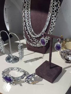 Серебристая коллекция: браслеты, кольца и серьги с аметистовыми вставками на темной подставке, демонстрация ассортимента Claudio Canzian.