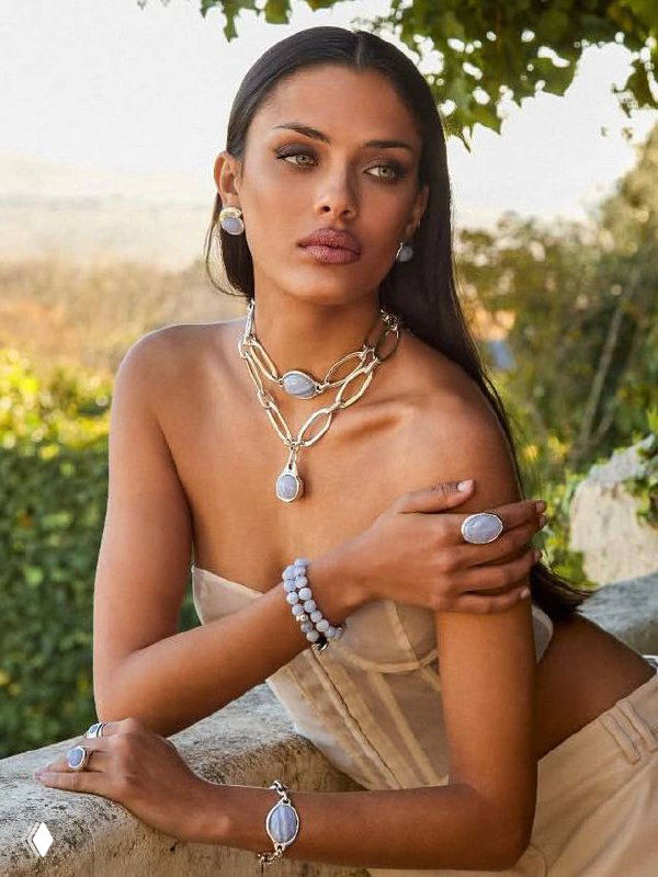 Модель в корсетном топе носит многослойные ожерелья и кольца VIDDA — студийная съёмка подчёркивает изысканный летний образ и золотые акценты