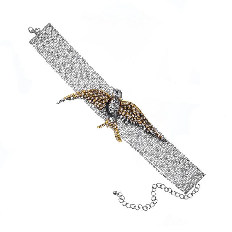 Браслет-манжет с металлической сеткой и фигурной птицей в центре, комбинированные металлы и кристаллы на белом фоне.