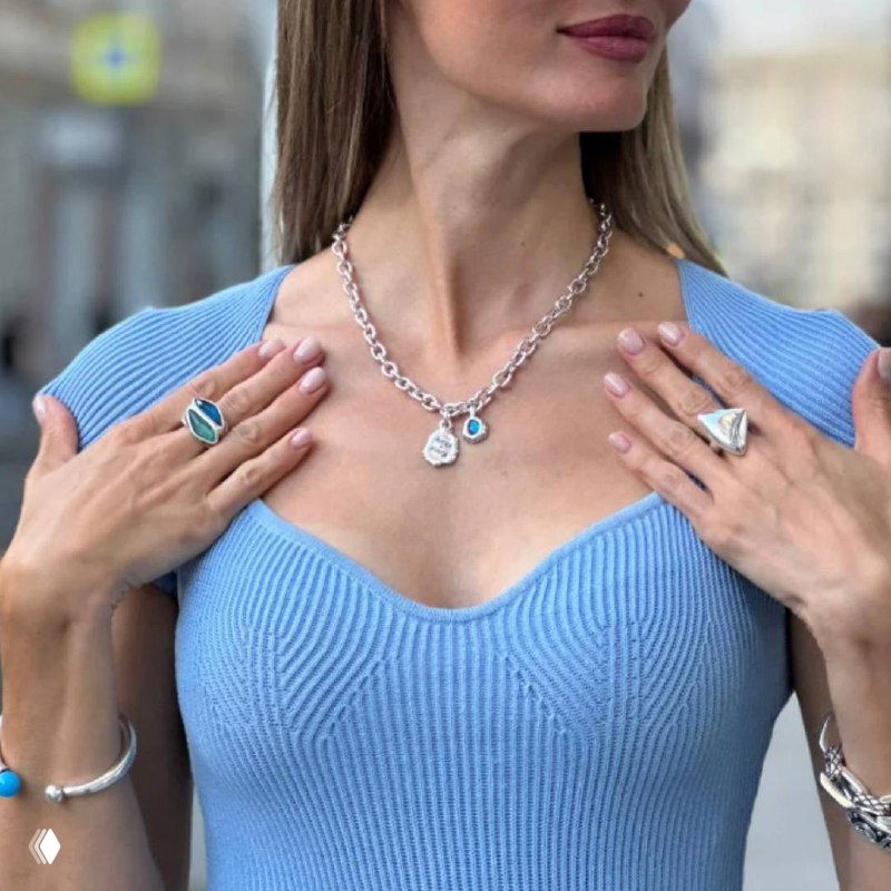 Модель в голубом трикотаже демонстрирует ожерелье и кольца Ciclon: серебряные подвески с бирюзовыми вставками в повседневном образе.