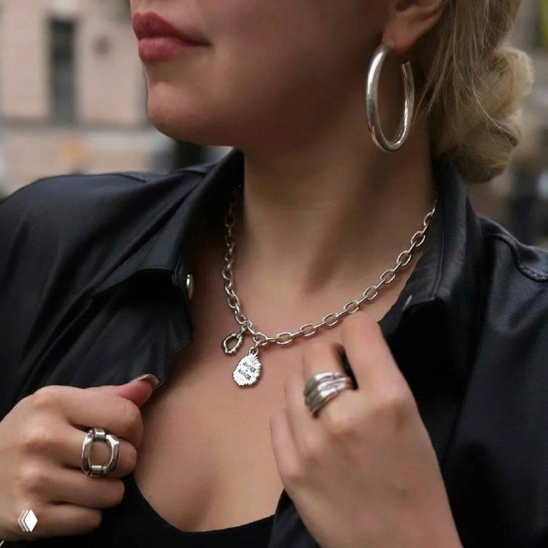 Крупный кадр шеи и подбородка модели в кожаной куртке: ожерелье-цепочка Ciclon и несколько колец — городской стиль и текстура металла.