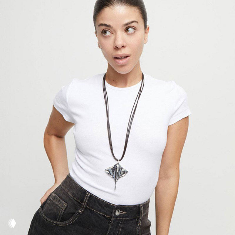 Модель в белой футболке и джинсах демонстрирует кулон-скат на длинной цепочке — стильный повседневный вариант из коллекции Ser Majestuosa.
