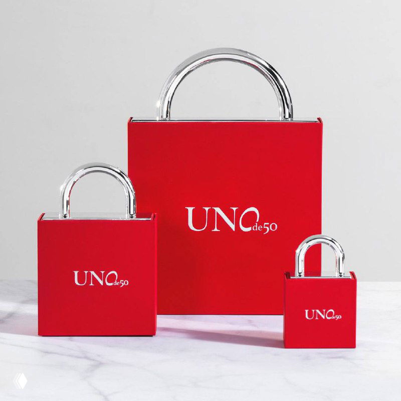 Красная фирменная упаковка UNOde50 на светлой поверхности — коробки и логотип бренда, отражающие фирменный стиль и презентацию изделий.
