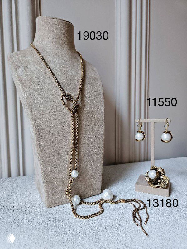 Фотография комплектов Claudio Canzian с белым жемчугом: длинное колье, браслет-ожерелье и серьги на бархатном манекене с указанными артикулами и ценами.