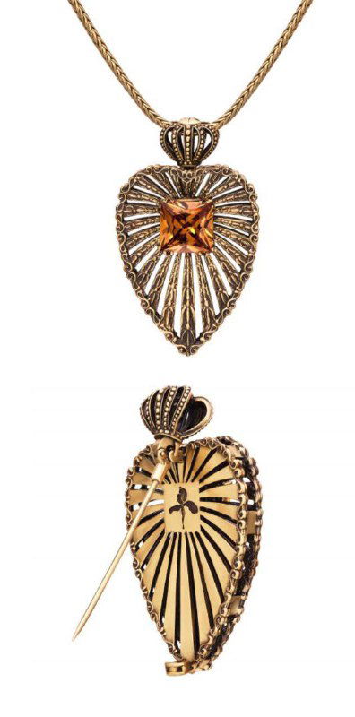 Крупный план подвески‑броши Fiore di Firenze: ажурная металлическая форма с янтарной вставкой и механизм превращения в подвеску