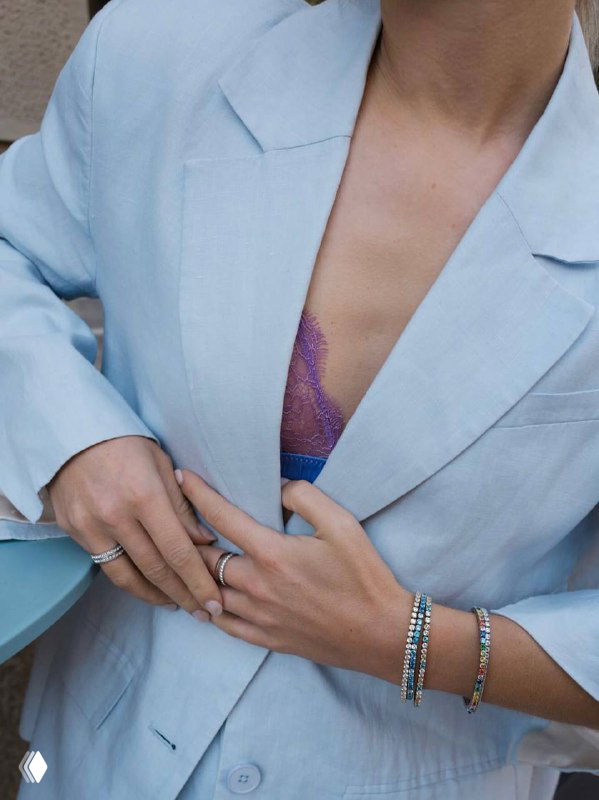 Крупный план рук и декольте в лёгком жакете, демонстрация колец и браслетов в сочетании с пастельной одеждой для летней коллекции