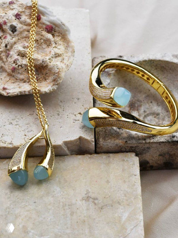 Ювелирные изделия на нейтральной каменной поверхности: золотой комплект с голубыми вставками, предметная фотосъёмка для каталога