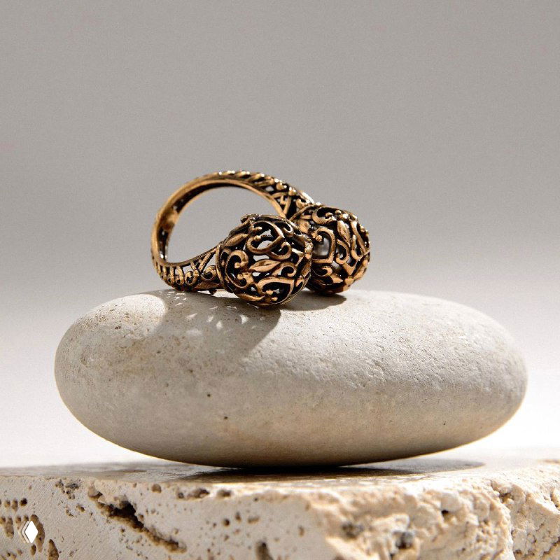 Кольцо SFERA (Fiore di Firenze) в тёплом бронзовом оттенке: две орнаментальные сферы, одна с тёпло-серой жемчужиной, на светлом камне.