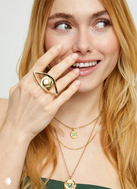 Рекламная фотография: модель демонстрирует кольцо в форме глаза и несколько золотых цепочек на шее, визульный образ коллекции Ser Intuitiva.