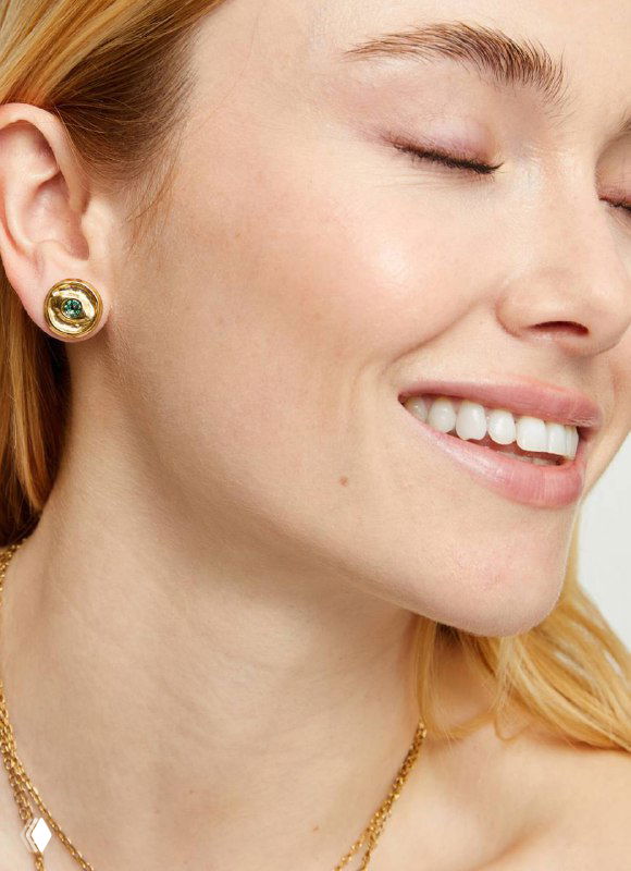 Сбоку портрет модели с небольшими золотыми серьгами и нежной улыбкой — стильная презентация аксессуаров коллекции Ser Intuitiva.