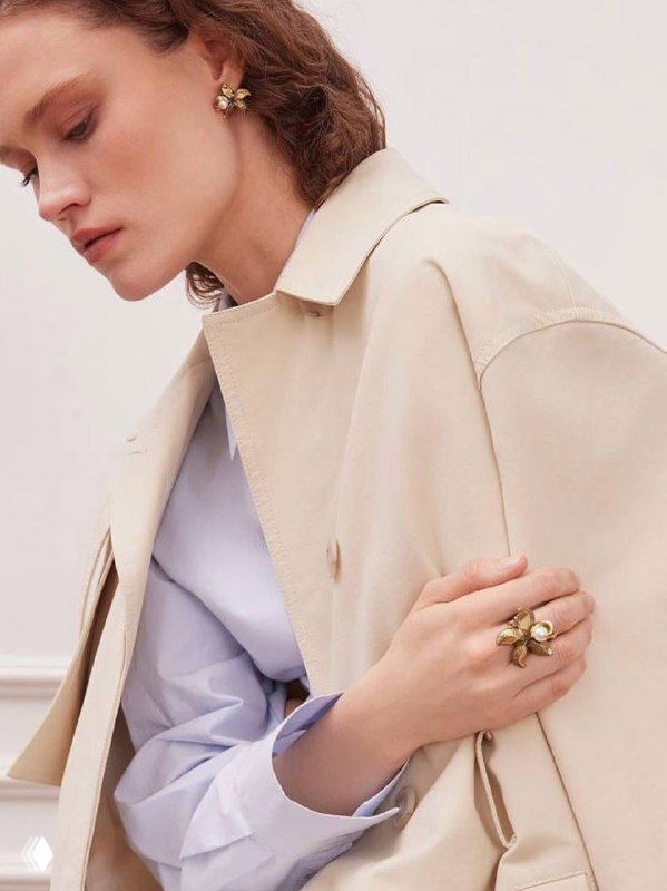 Модель в бежевом пальто и нейтральном образе: крупный план руки с кольцом и жемчужным акцентом, подчёркивающий аксессуары в стиле Fiore di Firenze.