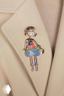 Фотография броши-куклы NO SECRET, закреплённой на бежевом пиджаке; металлическая брошка с ручной эмалью, позолотой и подвесными ножками для декора образа.