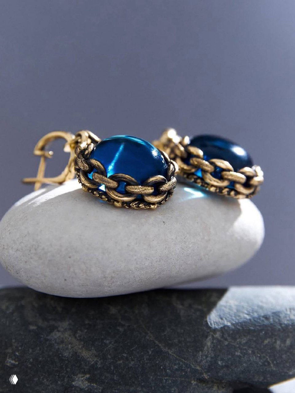 Макро-снимок серьг из коллекции CATENE с глубоким морским кабошоном в обрамлении винтажной золотистой цепи и фактурной оправой, студийный фон.