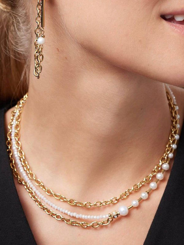 Крупный план ожерелья и браслетов: сочетание золотых цепочек и мелких жемчужин на шее, акцент на текстуре металла и жемчуга в каталоге.