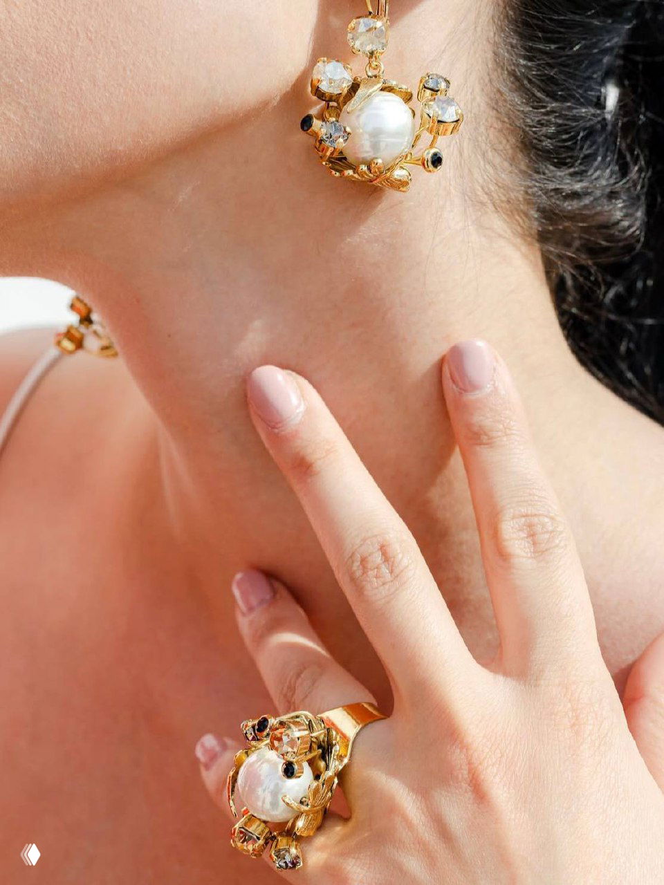 Макро-съёмка золотой серьги с большой барочной жемчужиной и инкрустированными кристаллами — детальная демонстрация дизайна и фактуры украшения.