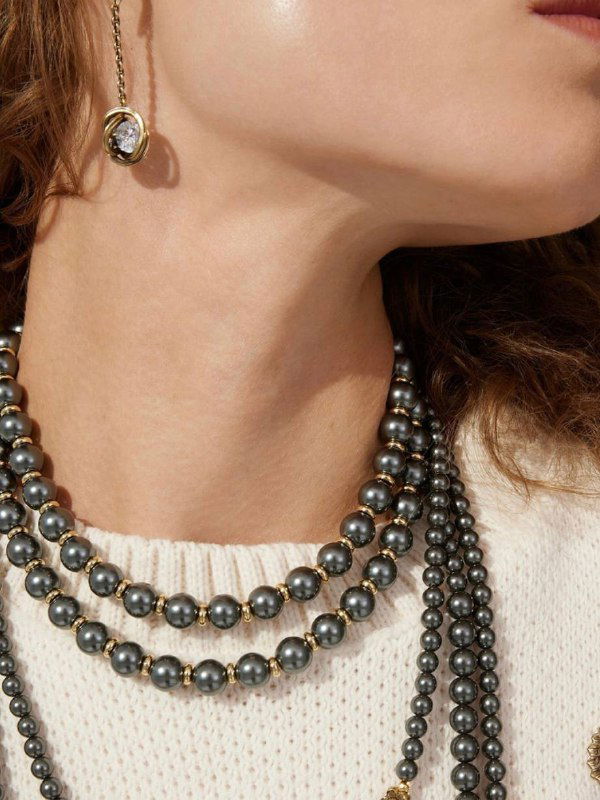 Пара изящных серьг с подвесной круглой жемчужиной и инкрустацией цирконами на нейтральном бежевом фоне, демонстрация классического дизайна.