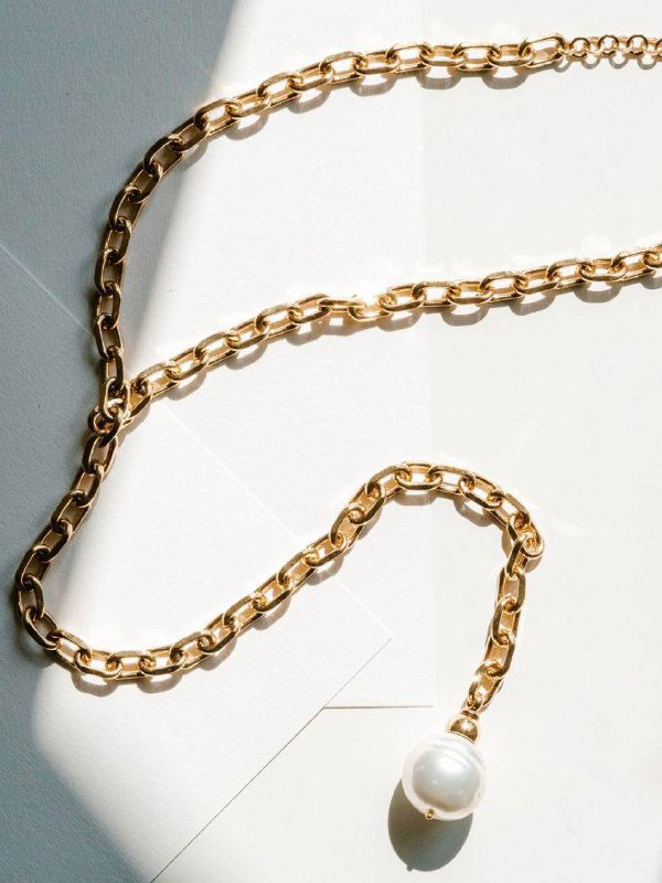 Модель в светлой одежде носит несколько нитей тёмно-серого жемчуга — многослойный стиль с насыщенным цветом и благородным блеском для повседневного образа.