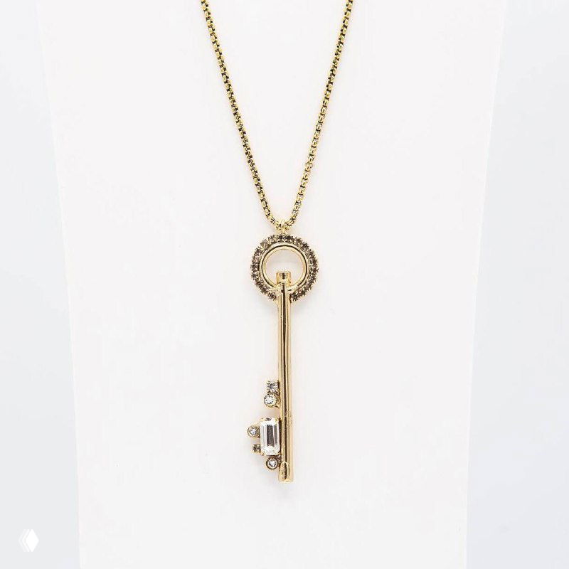 Золотая цепочка с подвеской-ключом на белом манекене, минималистичный дизайн кулона и длина цепи выделены в студийном представлении украшения.