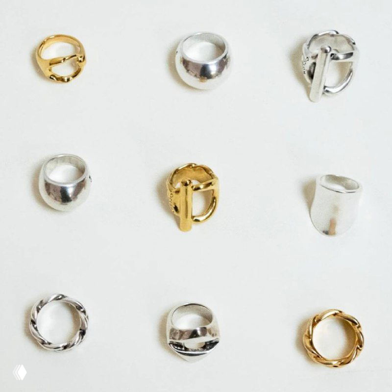 Ряд золотых и серебряных колец разного дизайна, аккуратно разложенных на светлом фоне для демонстрации форм и фактур коллекции CICLON.