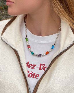 Модель в ожерелье Ciclon LIQUID: крупные разноцветные муранские вставки на цепочке, кадр показывает контраст ярких стеклянных элементов и одежды.