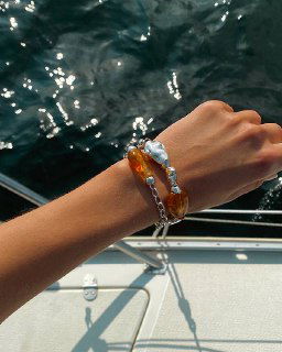 Браслет Ciclon LIQUID на фоне морской воды: прозрачные и янтарные муранские элементы отражают солнечный блик и подчёркивают летнюю концепцию коллекции.