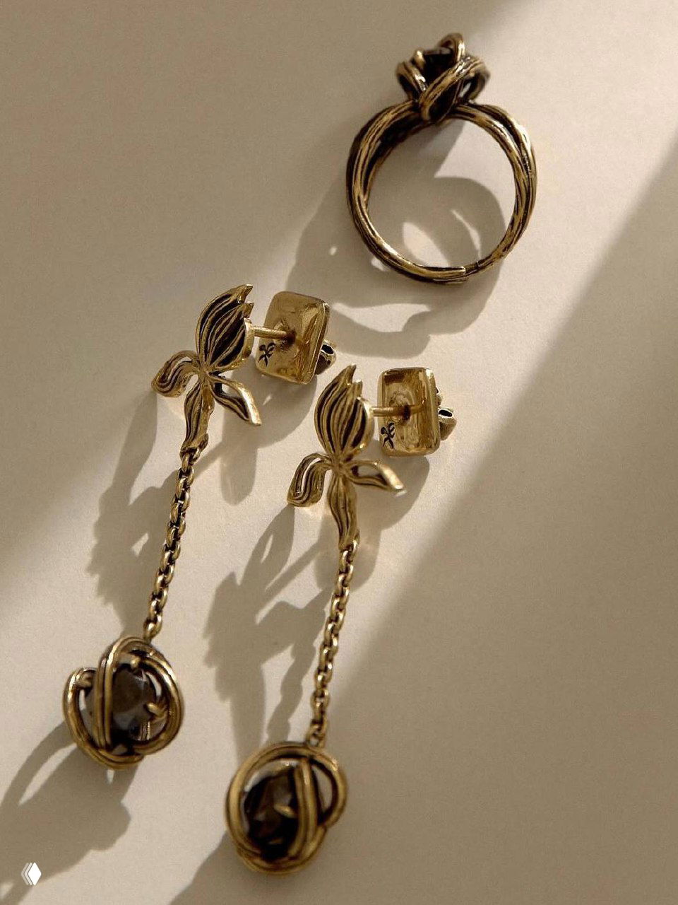 Плоская композиция: золотистые серьги-пуссеты и длинные подвесы Fiore di Firenze на светлом фоне — тёплые блики и тени.