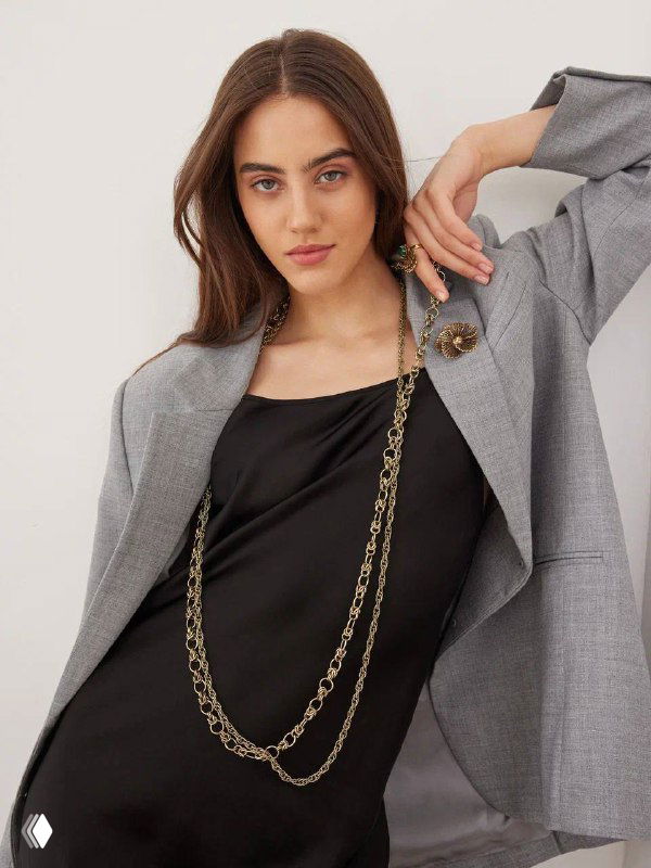 Модель в светлом пиджаке с длинной цепью и брошью, украшения Fiore di Firenze подчёркивают деловой образ — лук для каталога.