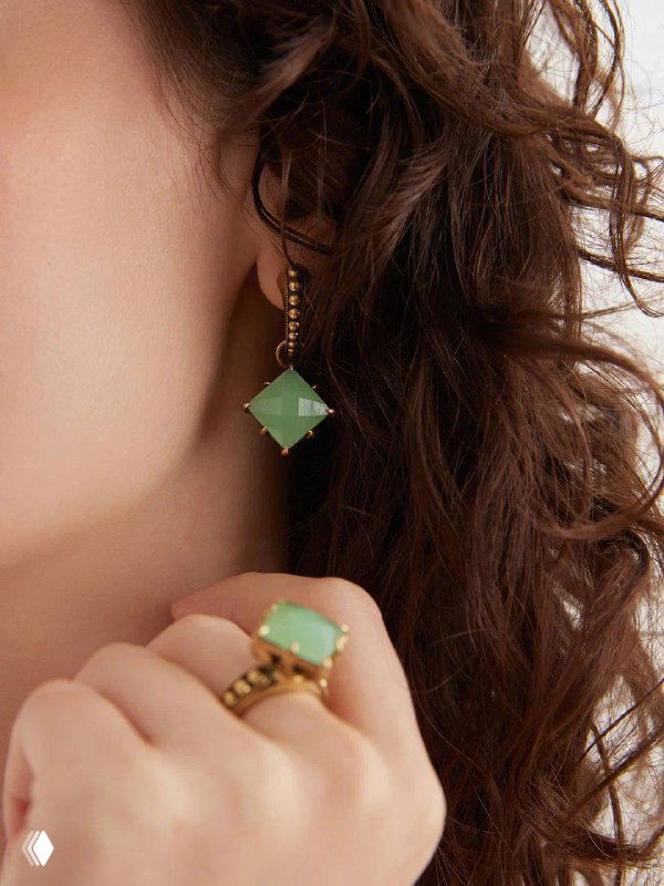 Модель в серьге с зелёной подвеской и кольцо с зелёным камнем на пальце — акцент на цветных вставках и деталях коллекции Fiore di Firenze.