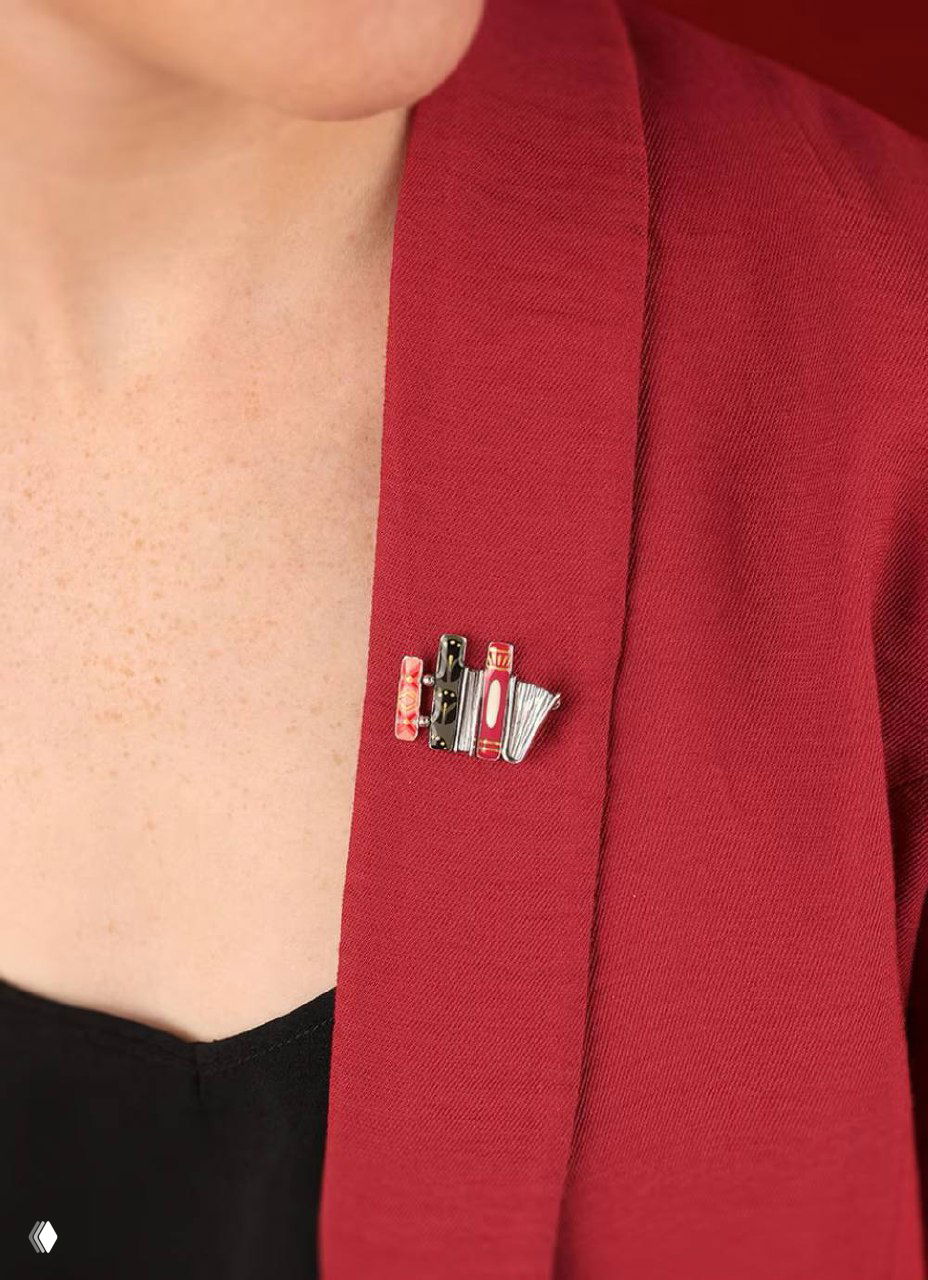 Брошь ROMANS, пришпиленная к лацкану бордового пиджака на модели: компактная композиция из мини-книг, подчёркивающая идею подарка для книголюба и учителя.