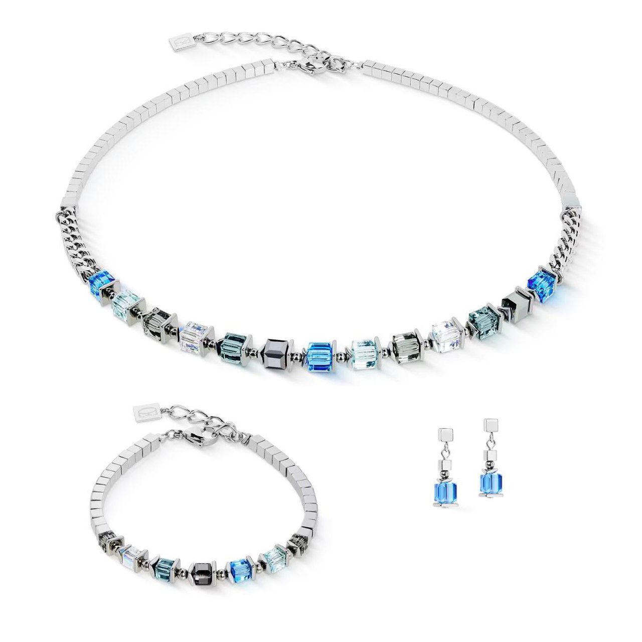 Серебристый комплект Coeur de Lion: колье, браслет и серьги с прозрачными и голубыми квадратными кристаллами на светлом фоне для интернет-магазина.