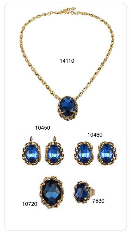 Комплект ожерелья, серег и колец Claudio Canzian с крупными синими кристаллами и золотистой оправой, показан на белом фоне