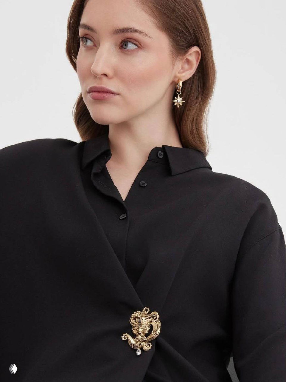 Портрет модели в серьге-звезде Fiore di Firenze и броши на чёрной рубашке; золотистые акценты подчёркивают простой осенний образ.