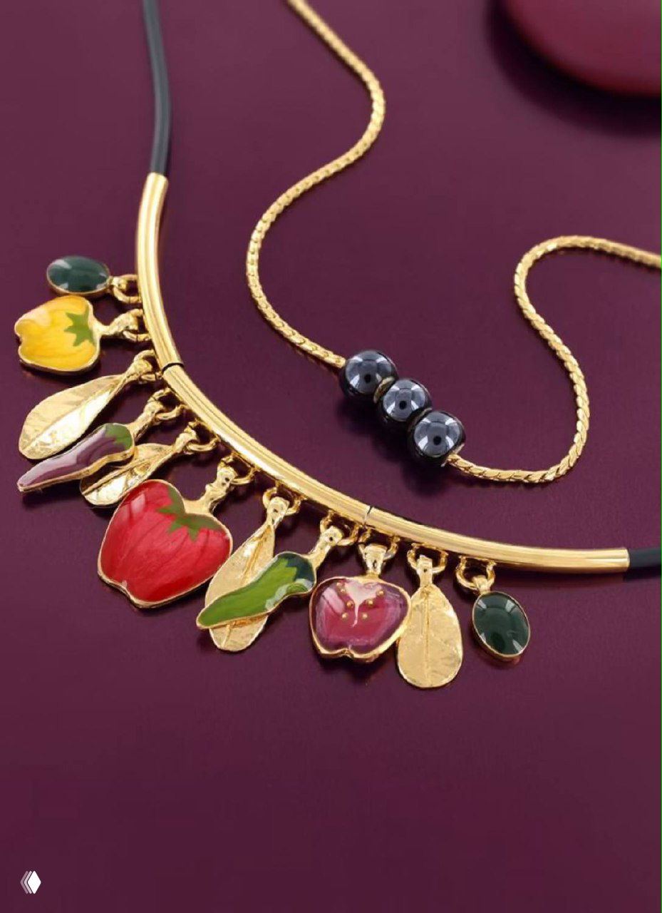 Колье TARATATA с разноцветными эмалевыми подвесками в форме фруктов и листьев, размещено на тёмно-бордовом фоне для контраста и демонстрации цвета.