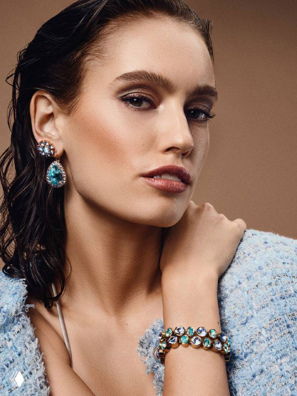 Портрет женщины в серьгах и браслете Dyrberg Kern с бирюзовыми кристаллами; акцент на украшениях и вечернем образе.