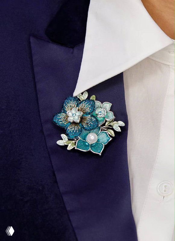Бирюзовая цветочная брошь на лацкане пиджака — эмалированная композиция с кристаллами, подчёркивающая женственность и утончённость аксессуара.