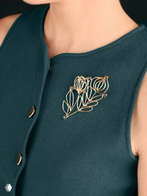 Брошь в форме филигранного листка из тонкой золотой проволоки на тёмно-зелёной ткани — минималистичная и изящная деталь для повседневного гардероба.