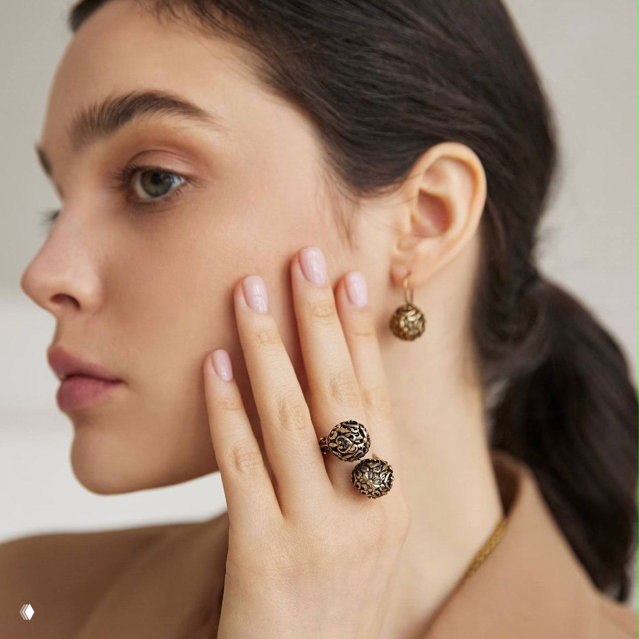 Модель в профиль с кольцом и серьгой SFERA: образ в повседневном стиле, показ посадки украшений на руке и ухе на нейтральном фоне.